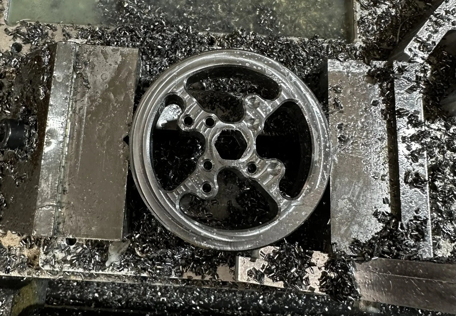 Custom aluminium flywheel surrounded by swarf on a CNC mill