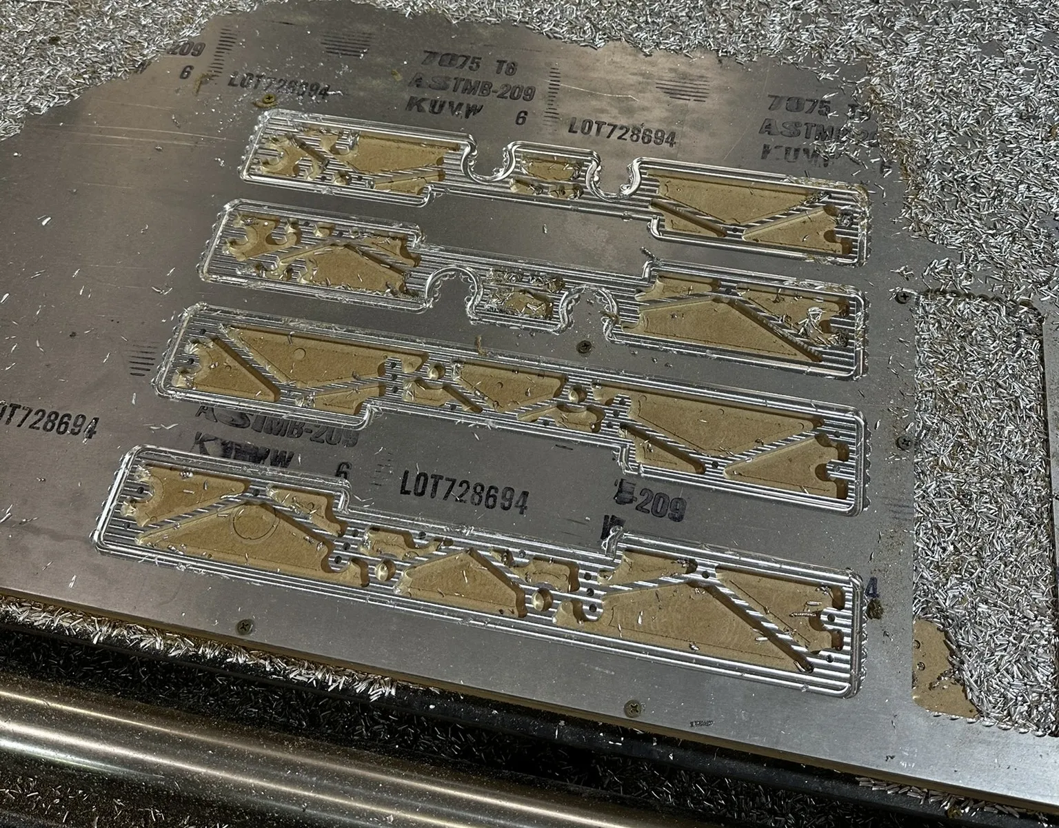 Several aluminium robot parts nested together on a CNC mill bed