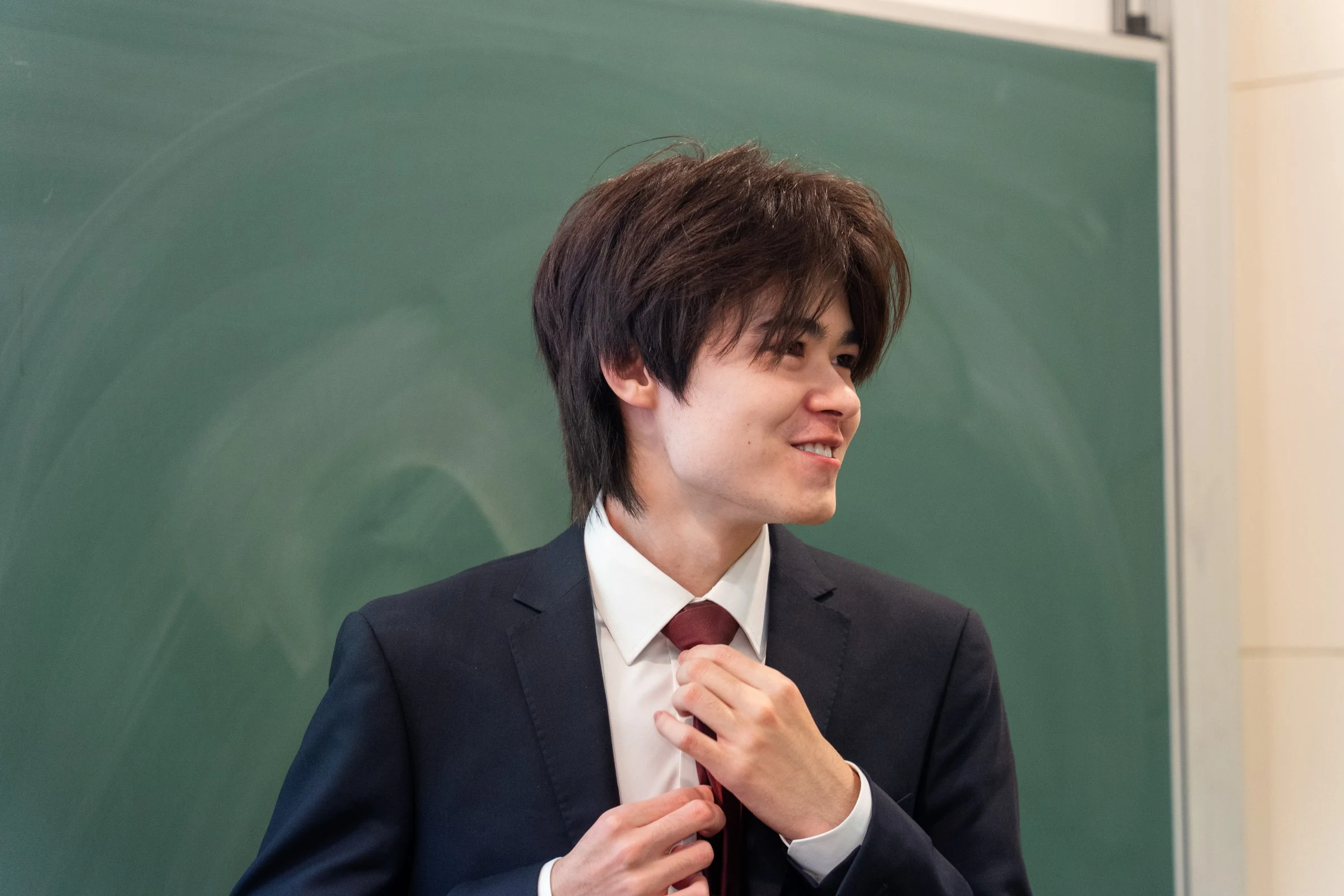 Jack Wilson adjusting his tie in front of a chalkboard