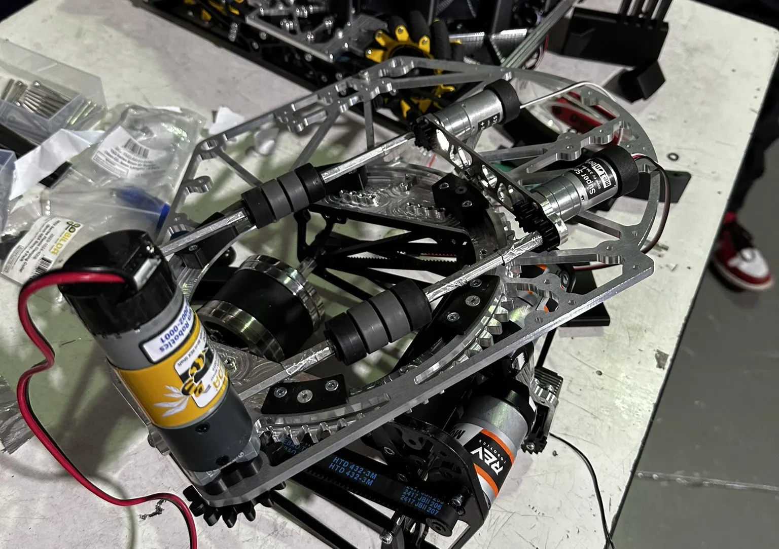 Assembled shooter and turret mechanism on a workbench beside the robot chassis